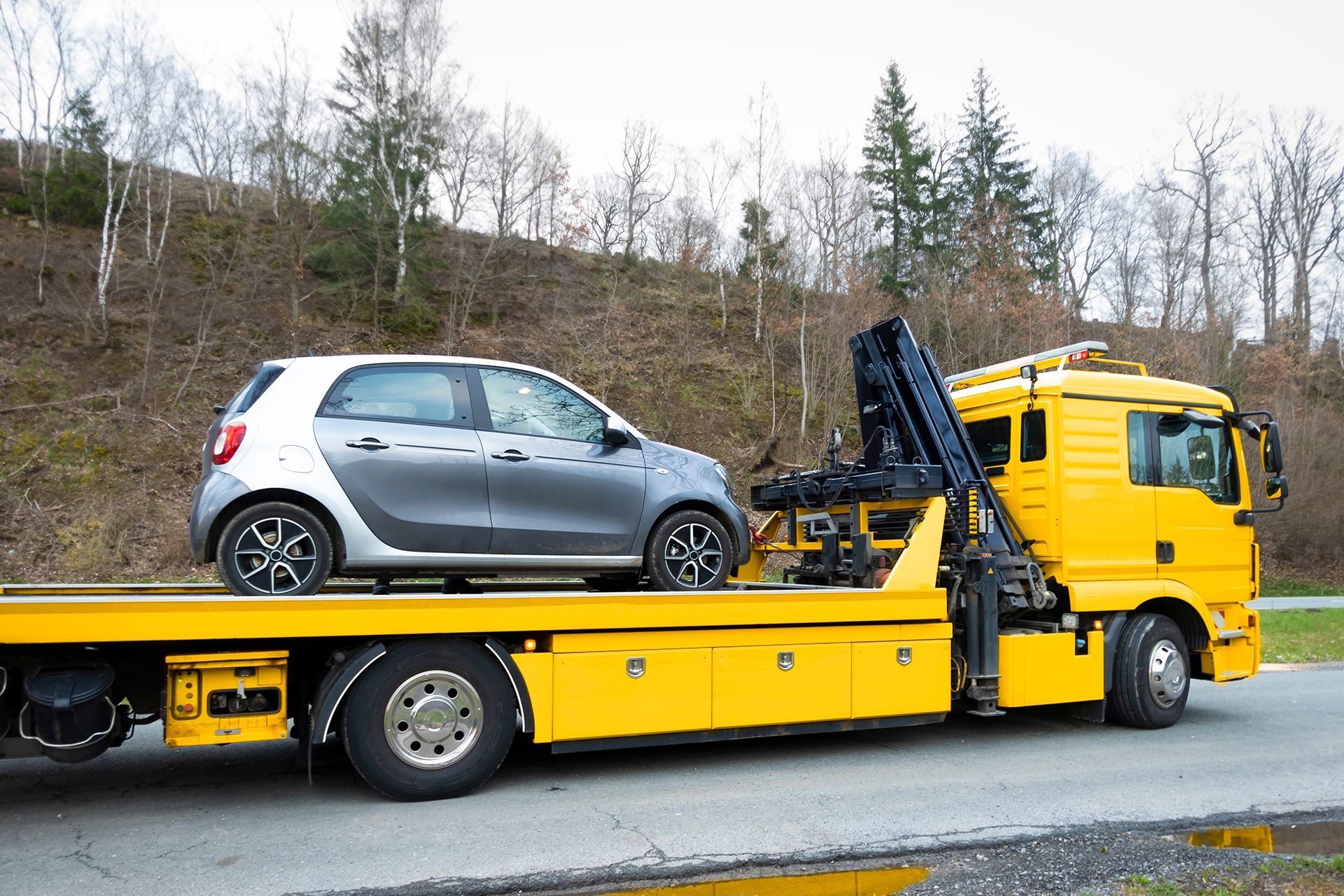 A tow truck is carrying a car on its flatbed.