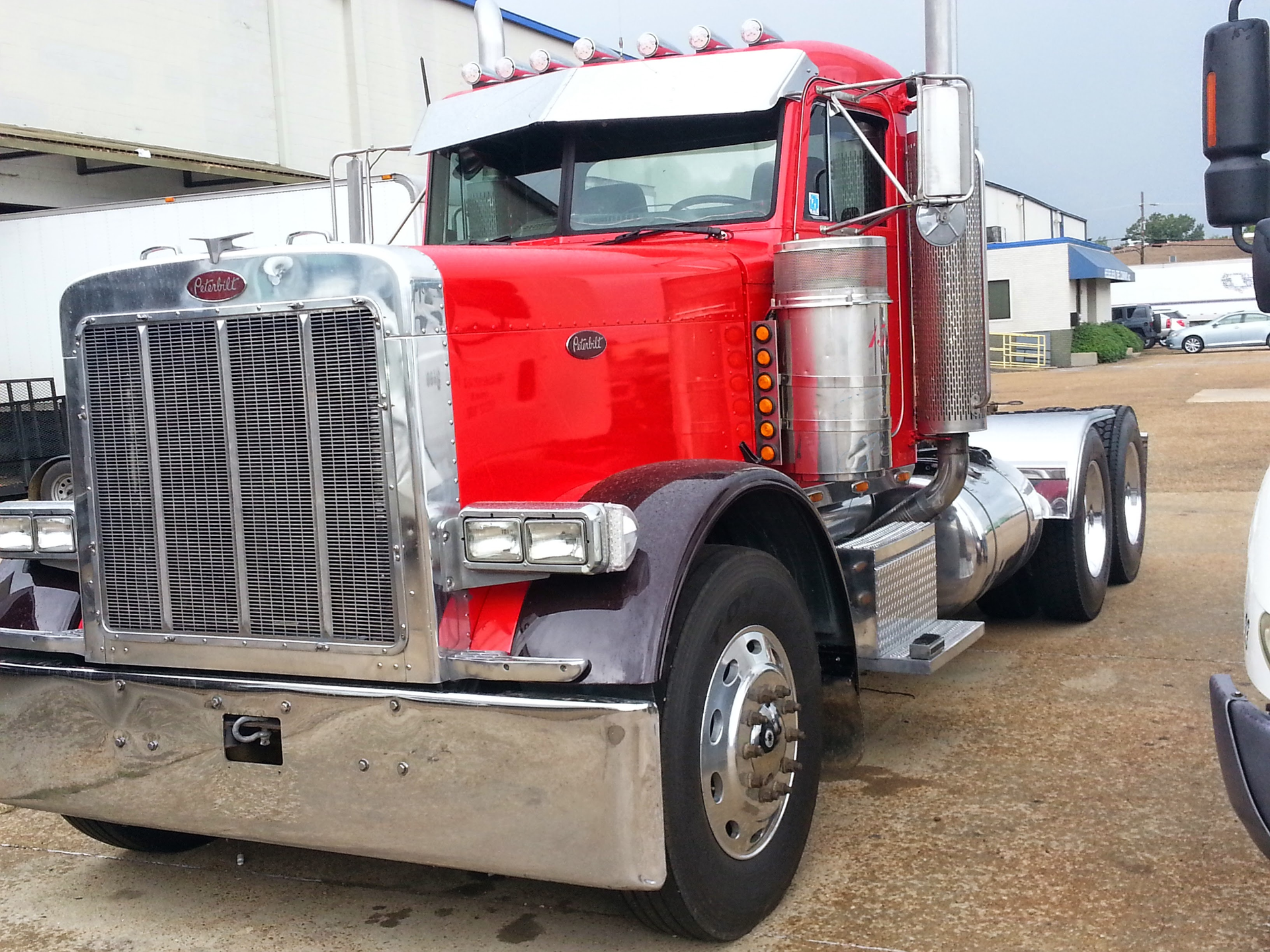 A red peterbilt semi truck is parked in a parking lot