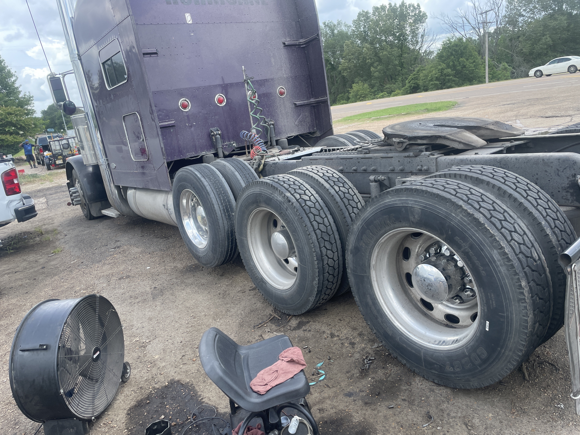 A purple semi truck is parked on the side of the road.