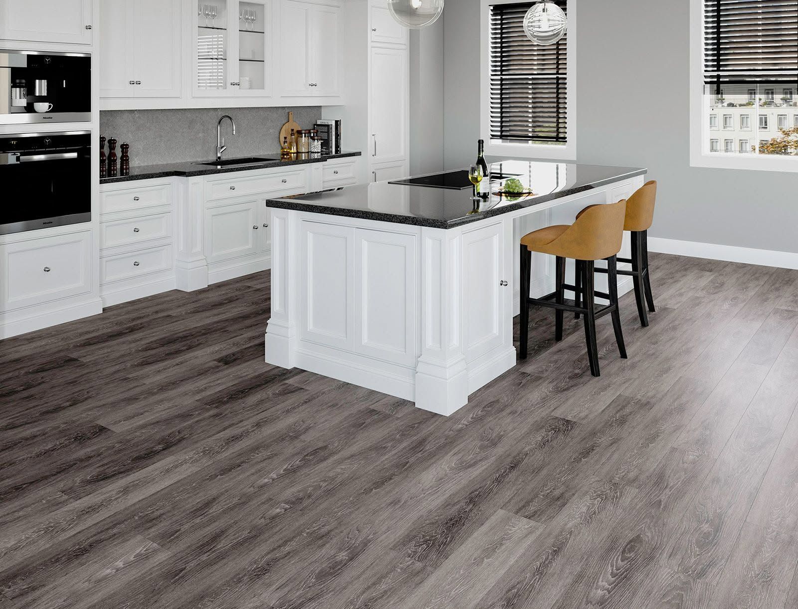Bright white kitchen with black countertops, island seating, and gray wood-look flooring