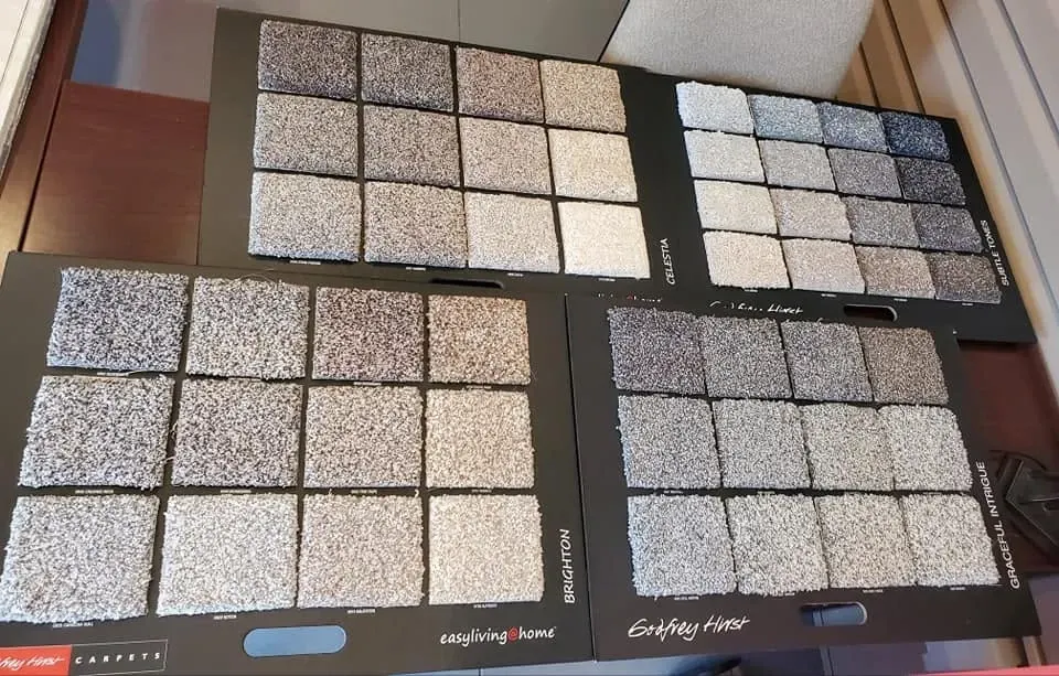 Four sample boards showing neutral speckled tile swatches in gray, beige, and black patterns.