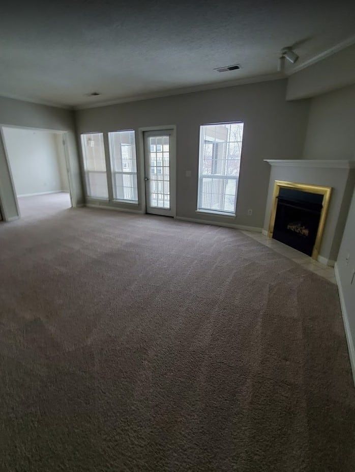 A modern living room with hardwood floors, a dark sofa, a coffee table, and large windows overlooking autumn trees.