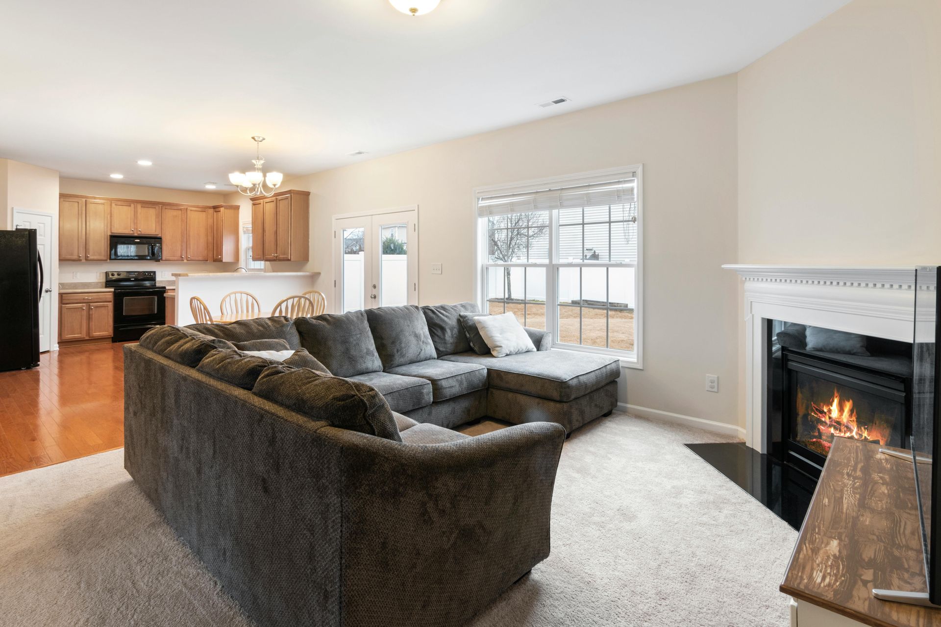 Bright living room with sectional sofa, fireplace, and open kitchen in the background
