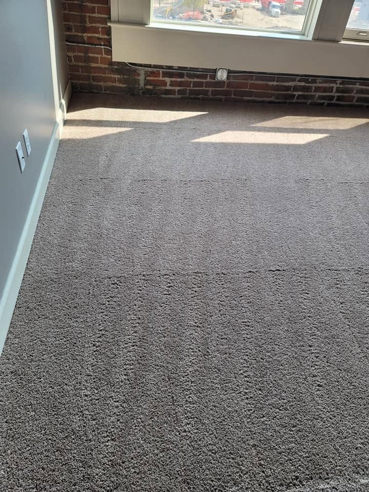 Empty carpeted room with sunlight from a window and a brick wall below it