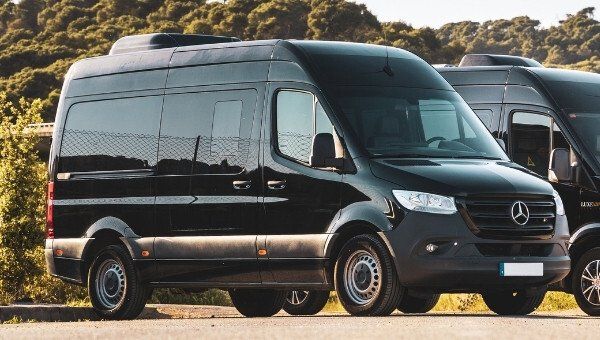 Dos furgonetas negras están estacionadas una al lado de la otra al costado de la carretera.