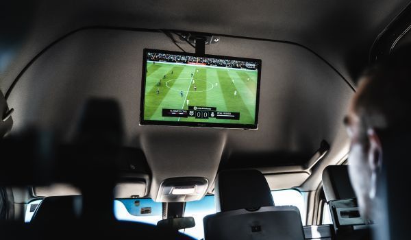 Una persona está viendo un partido de fútbol en un televisor montado en el techo de un automóvil.