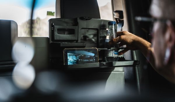 Un hombre está sentado en el asiento trasero de un automóvil sosteniendo una botella de agua.