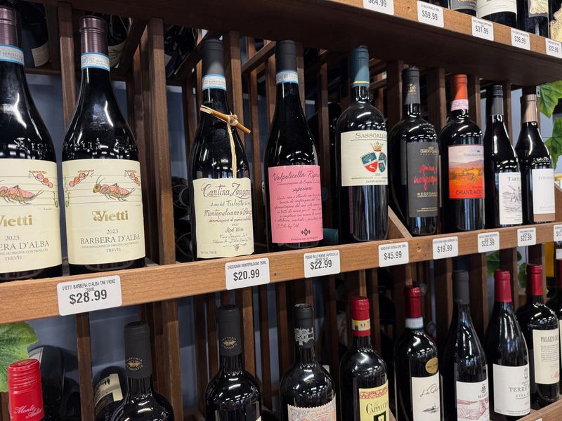 Italian red wines on a wooden rack including Barbera d'Alba and Valpolicella