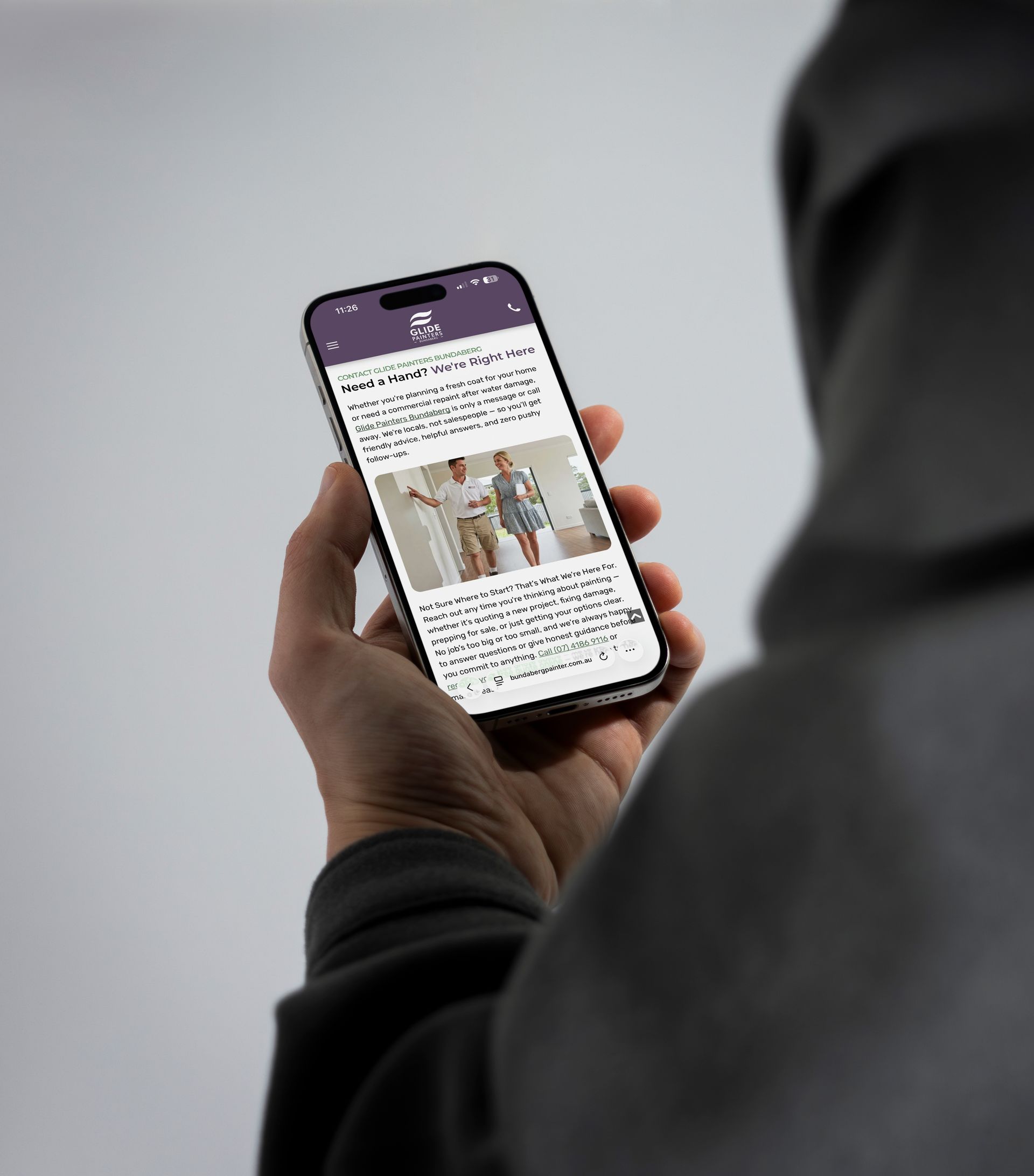 Person holding a phone, viewing a webpage with text and an image of people.