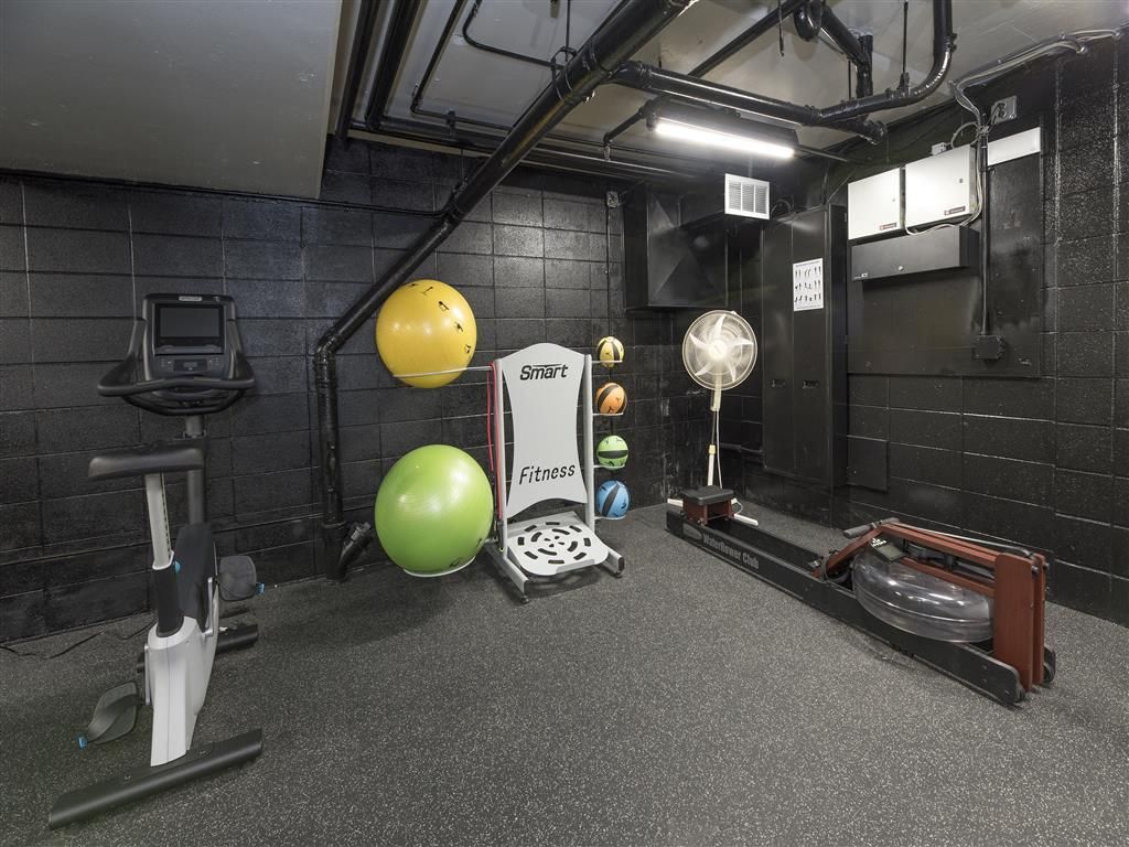 Basement-style gym with a treadmill, stationary bike, weights, and a fan at Tower apartments in Alameda, CA.