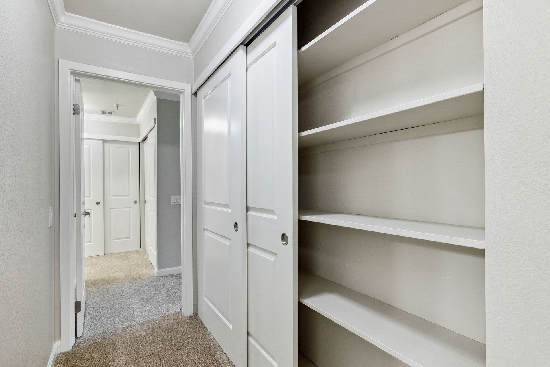 Hallway with built-in white closet shelves and sliding doors at Tower apartments in Alameda, CA.