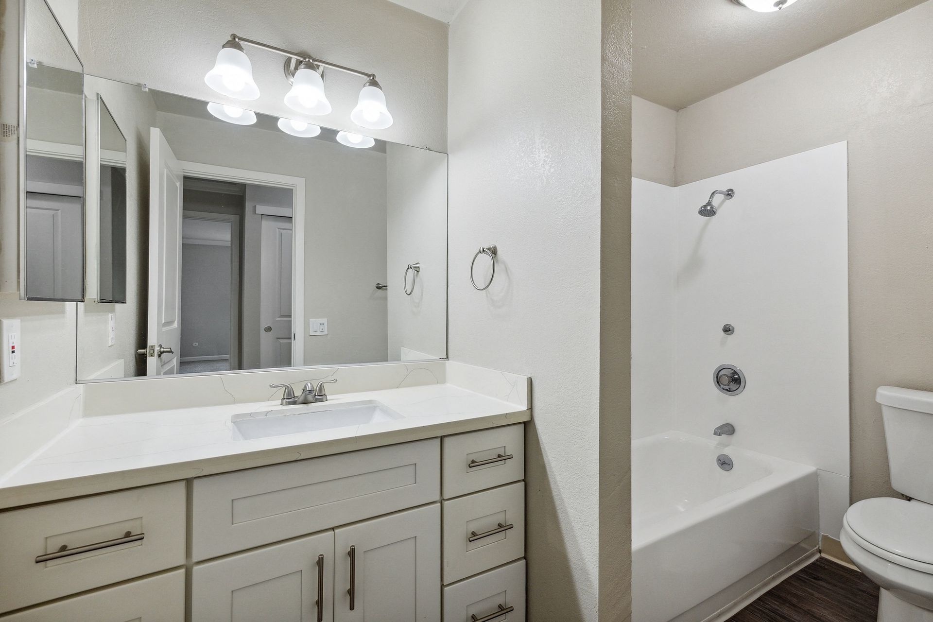 Bathroom with white vanity, large mirror, and a tub/shower combo at Tower apartments in Alameda, CA.