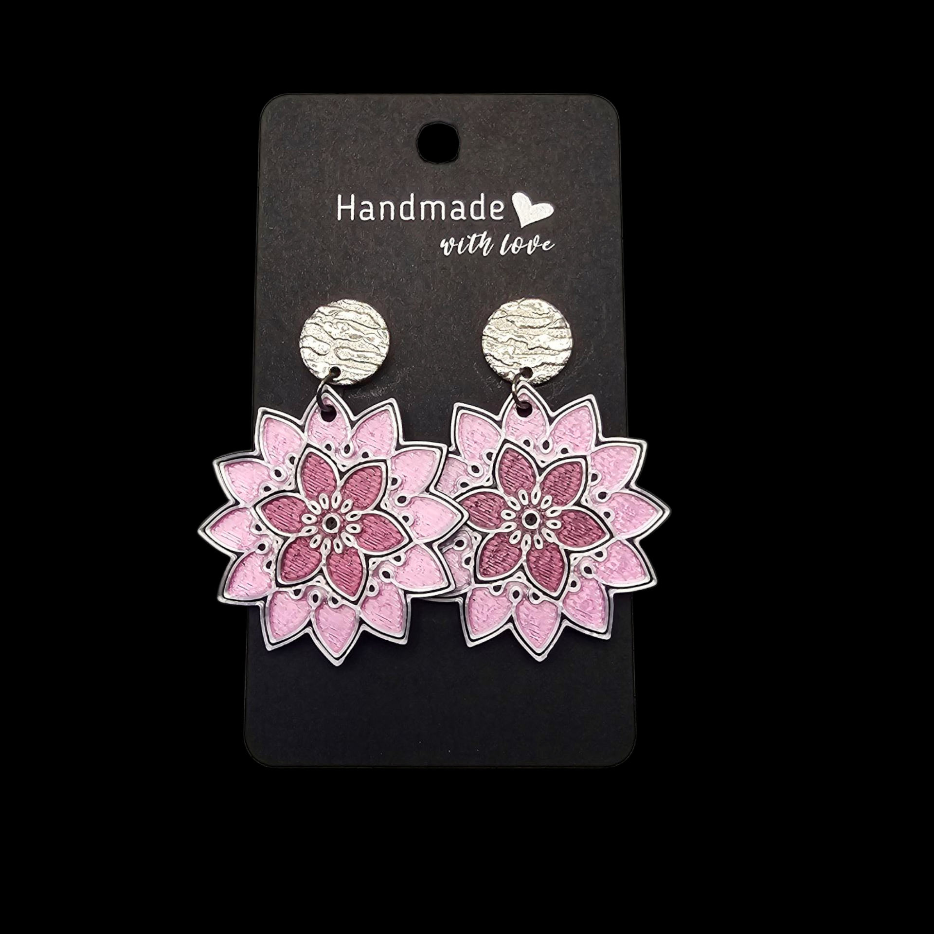 Een paar roze oorbellen in mandala-stijl met zilveren studs met een textuur, bevestigd aan een zwart "Handmade"-label.