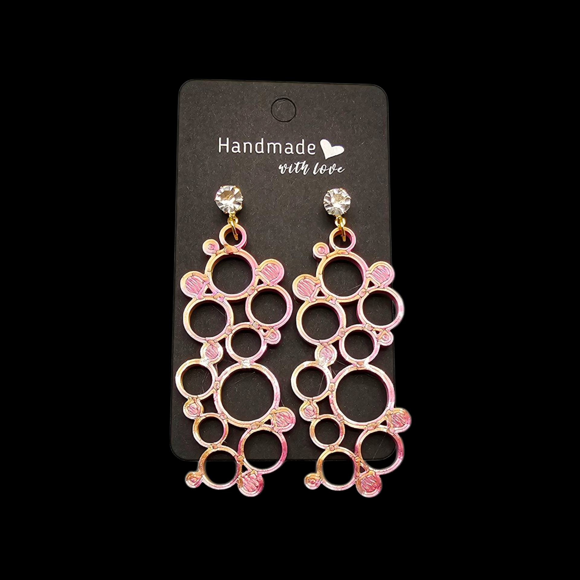 Een paar roze, ronde, bubbelvormige hangende oorbellen met strass-steentjes, gepresenteerd op een zwart, handgemaakt label.