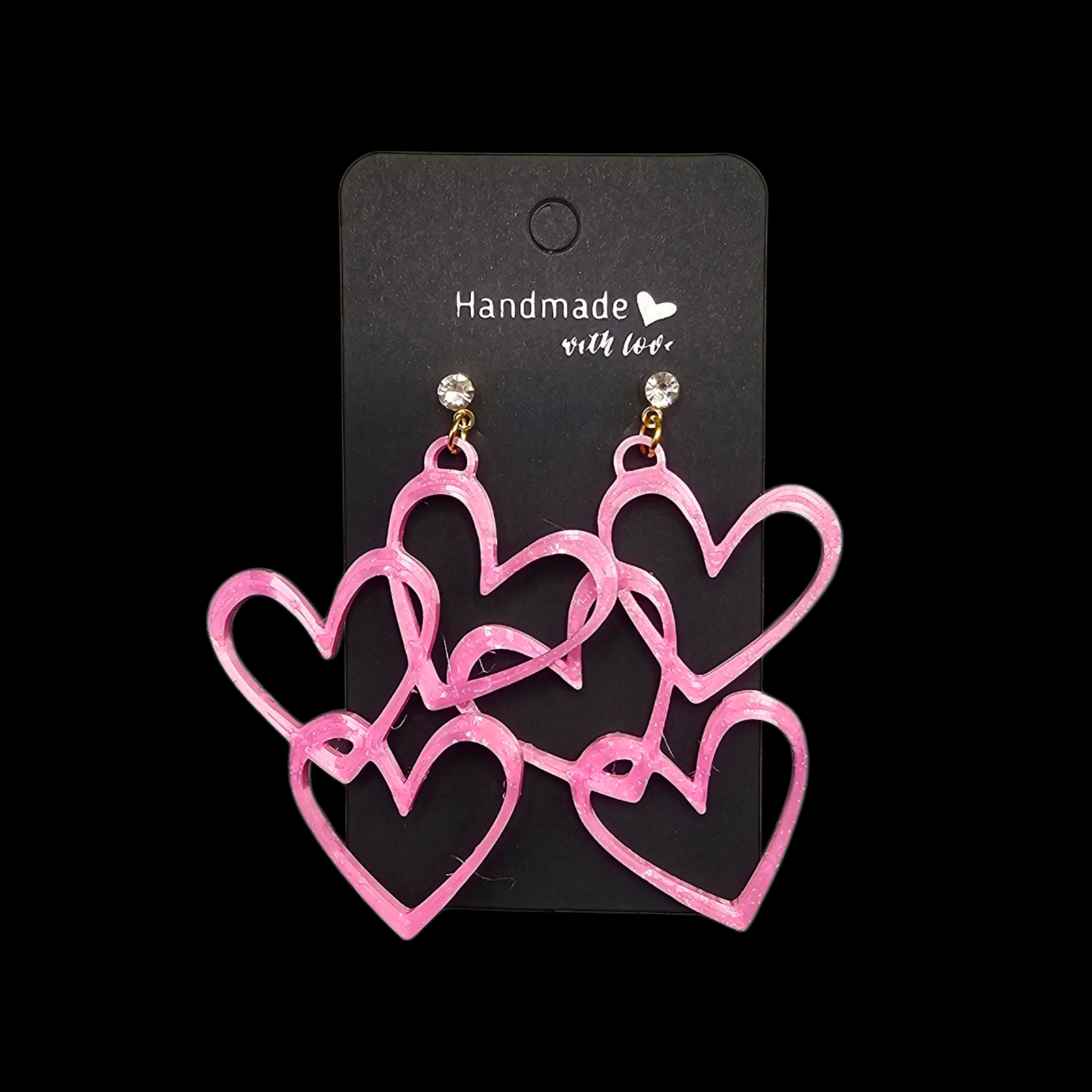 Een paar roze, open hartvormige hangende oorbellen, gepresenteerd op een zwart kaartje met de tekst "Handgemaakt met liefde".