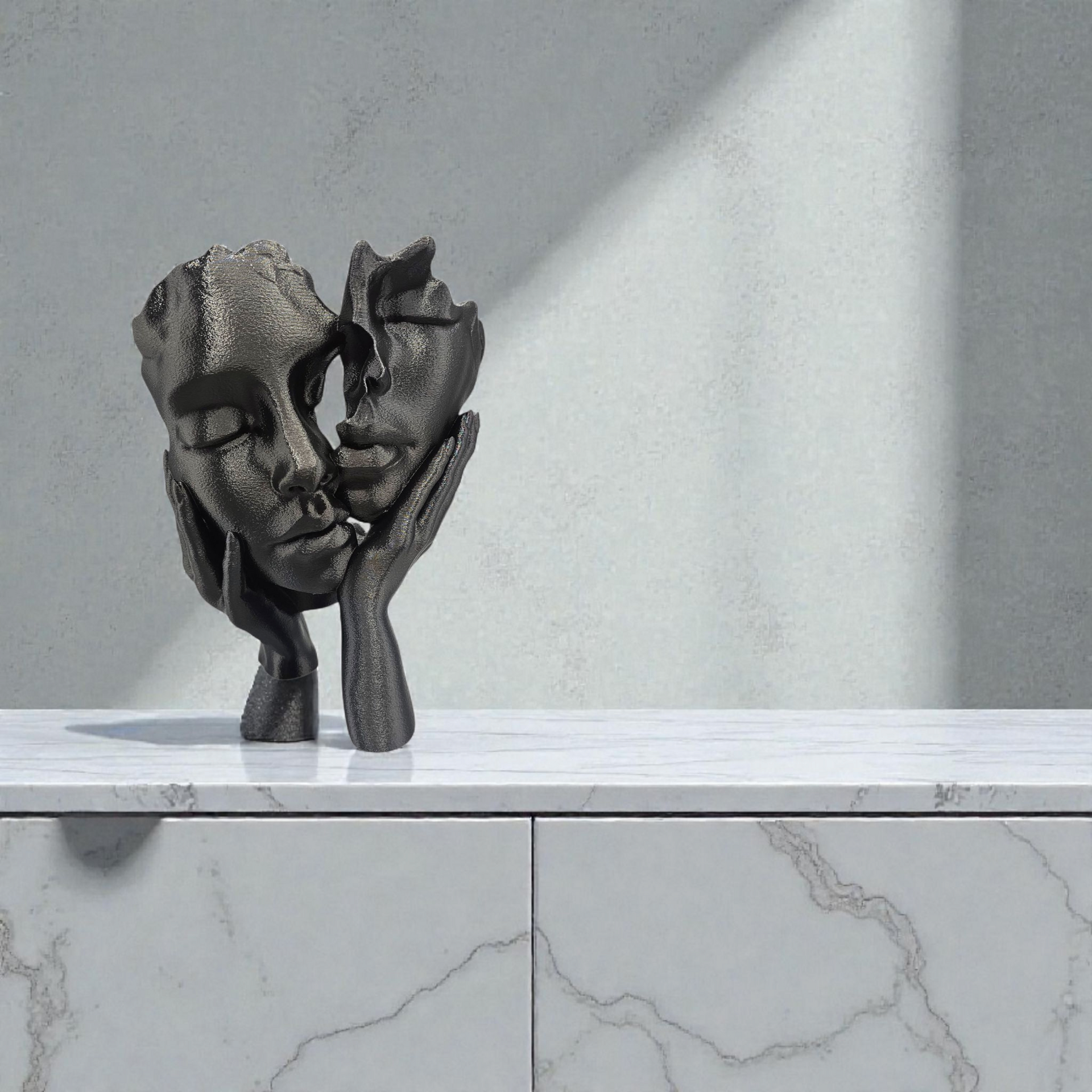 Een zwart, abstract sculptuur met textuur, voorstellende twee gezichten die door twee handen worden vastgehouden, tentoongesteld op een witte marmeren ondergrond.