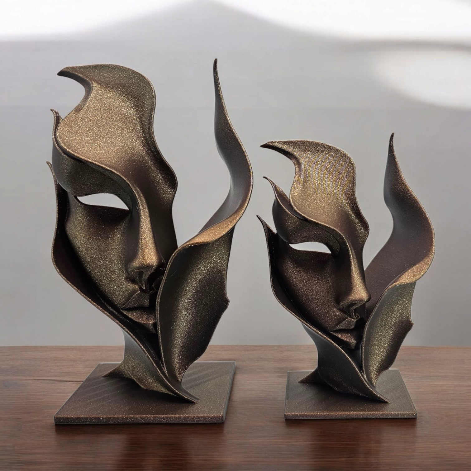 Een donkere, abstracte sculptuur met vloeiende, bloembladachtige vormen op een vierkante sokkel, geplaatst tegen een effen achtergrond.
