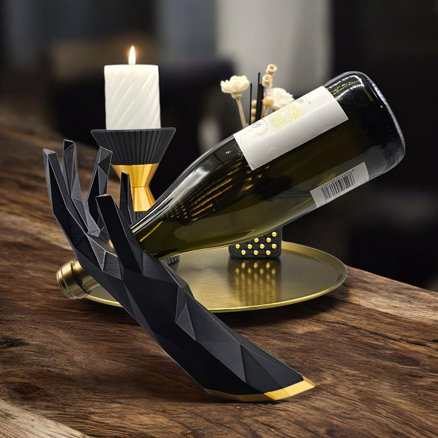 Een modern, zwart, geometrisch handbeeld op een houten tafel houdt een wijnfles vast, naast een gouden kandelaar.