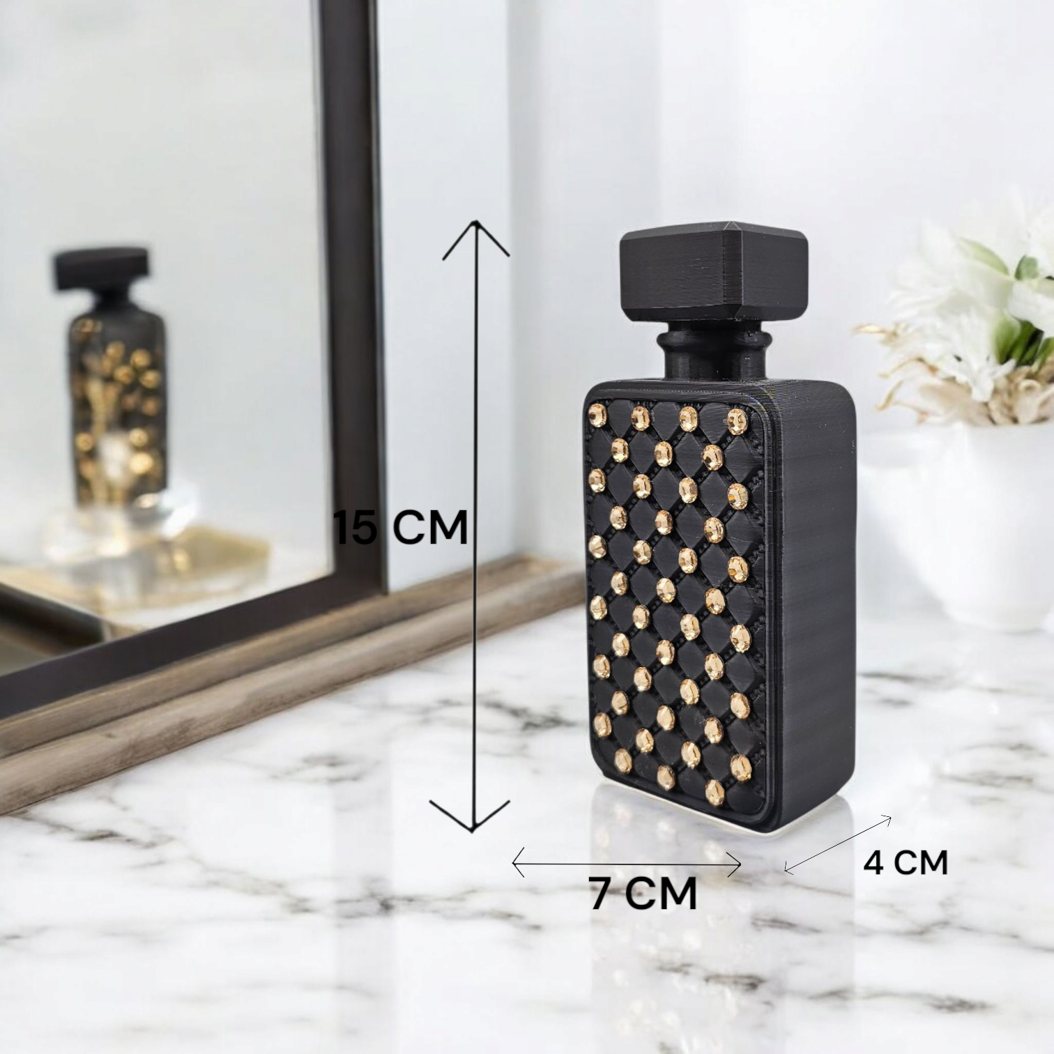 Een rechthoekig zwart parfumflesje met gouden studs, 15 cm hoog, 7 cm breed en 4 cm diep, staat op een wit marmeren oppervlak.