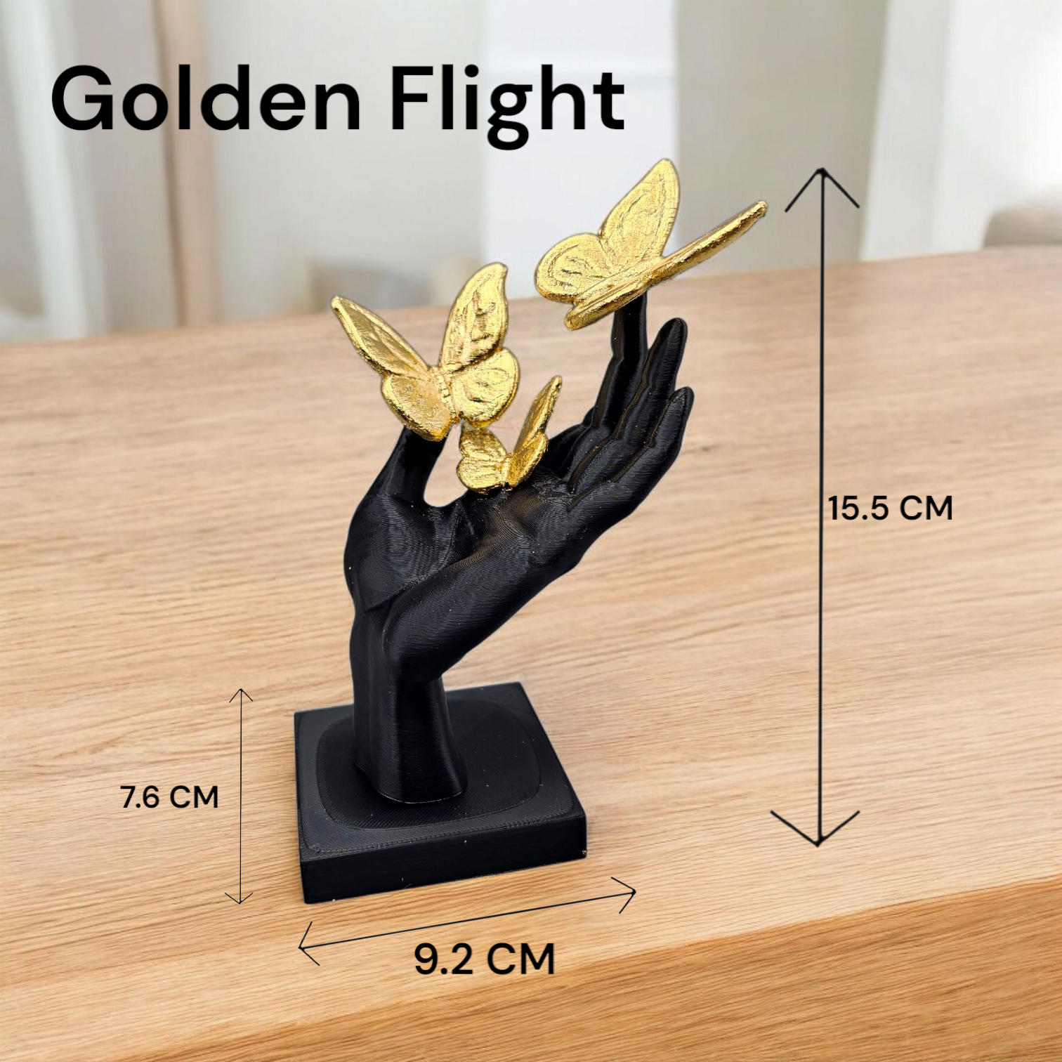 Een zwart handbeeld op een vierkante sokkel met twee gouden vlinders, voorzien van het opschrift