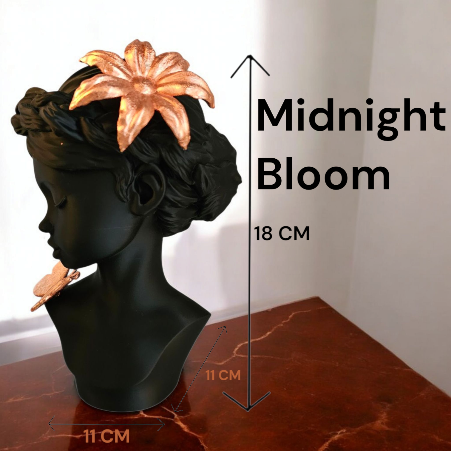 Een zwarte buste met een koperkleurig bloemaccessoire en een vlinder, met het opschrift