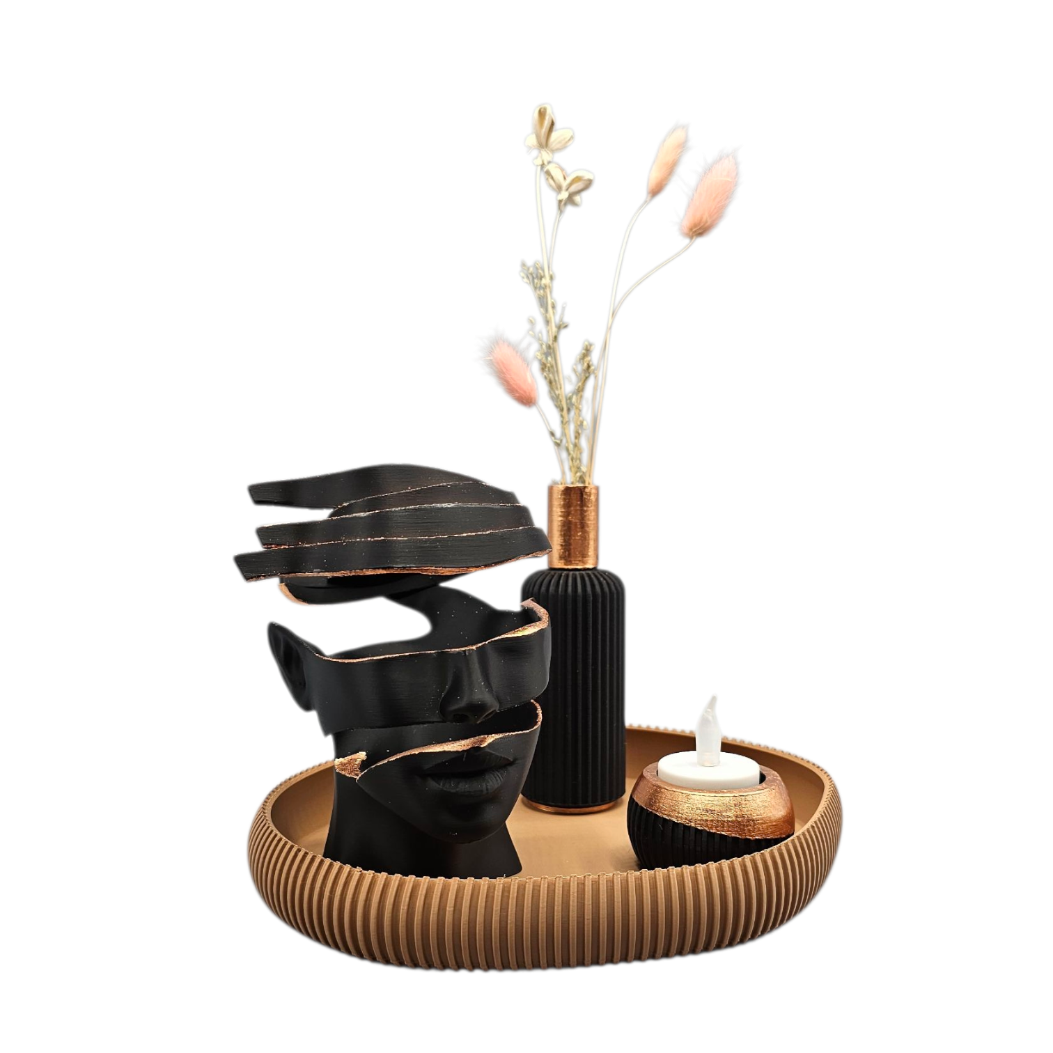 Op een rond dienblad staan een zwart abstract beeld, een klein vaasje met gedroogde bloemen en een theelichtje op een tafel.