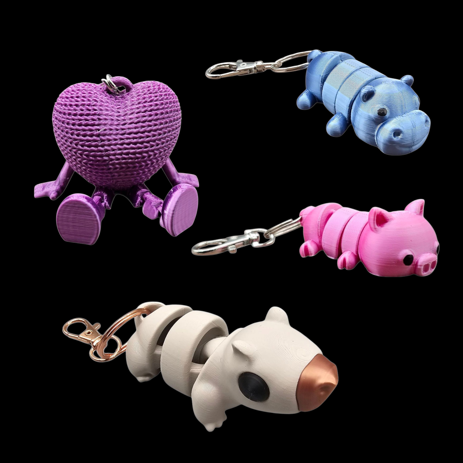 Vier 3d geprinte dieren sleutelhangers in paars, blauw, roze en wit op een zwarte achtergrond.
