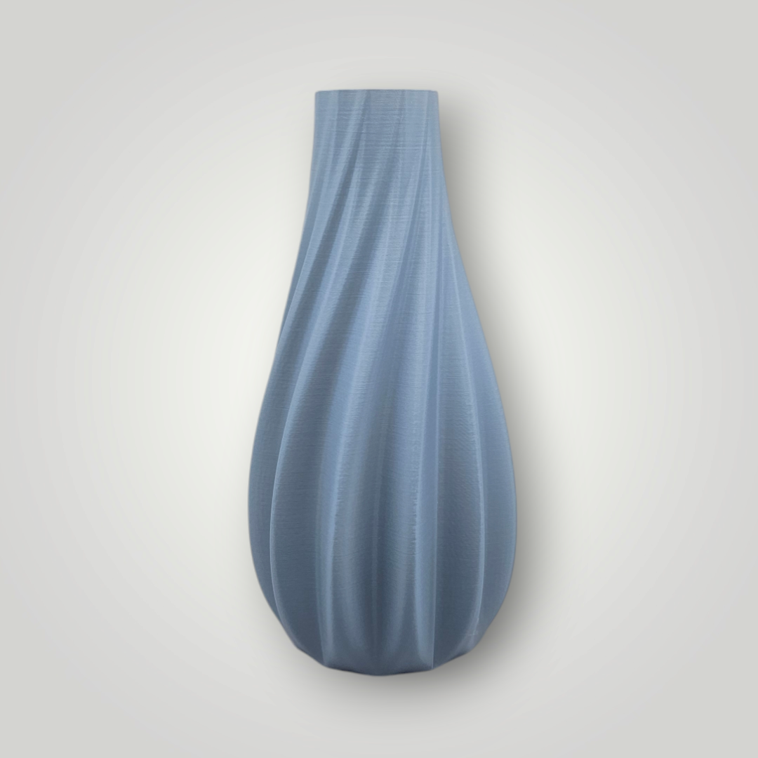 Een lichtblauwe, 3D-geprinte vaas met een verticaal geribbelde, spiraalvormige textuur op een effen witte achtergrond.