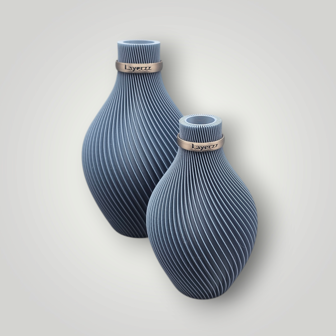 Twee grijze, 3D-geprinte vazen met een spiraalvormige textuur en metalen ringen rond de hals, geplaatst tegen een effen achtergrond.