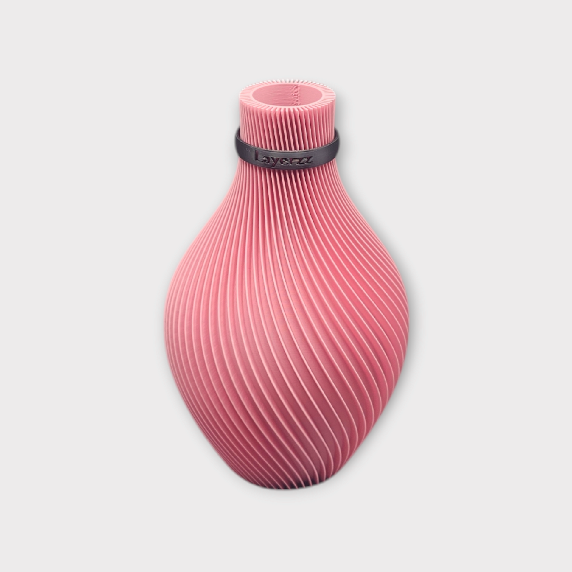 Een roze, 3D-geprinte vaas met een gestructureerd, spiraalvormig ribbelpatroon en een zwarte ring rond de hals.