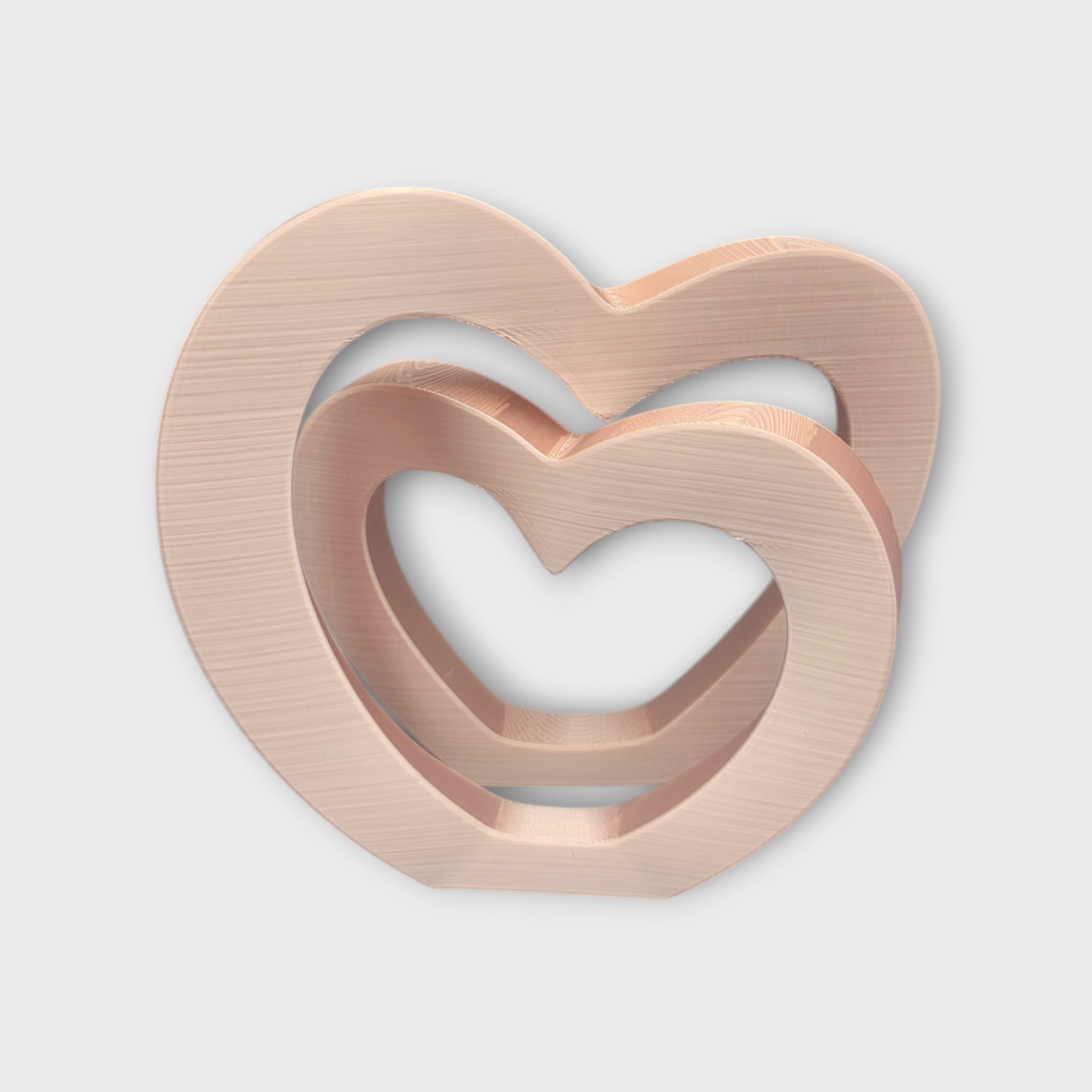 Een metallic rood 3D-geprint ornament met twee in elkaar grijpende hartvormen.