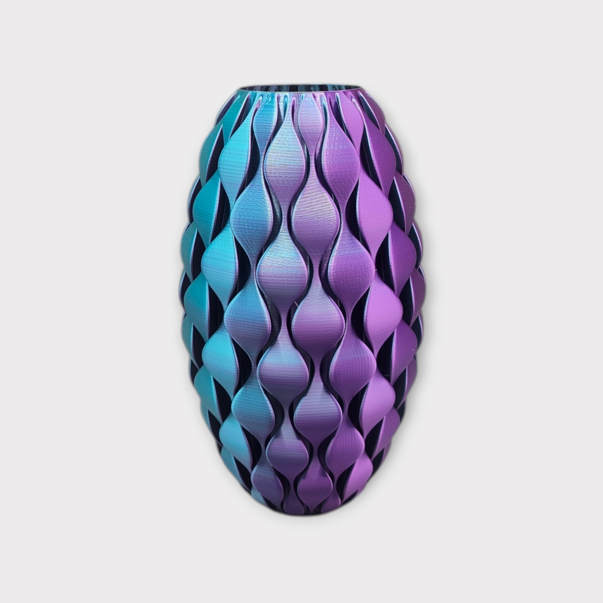 Een ovale vaas met een herhalend, gestructureerd golfpatroon, met een kleurverloop van turquoise naar paars.