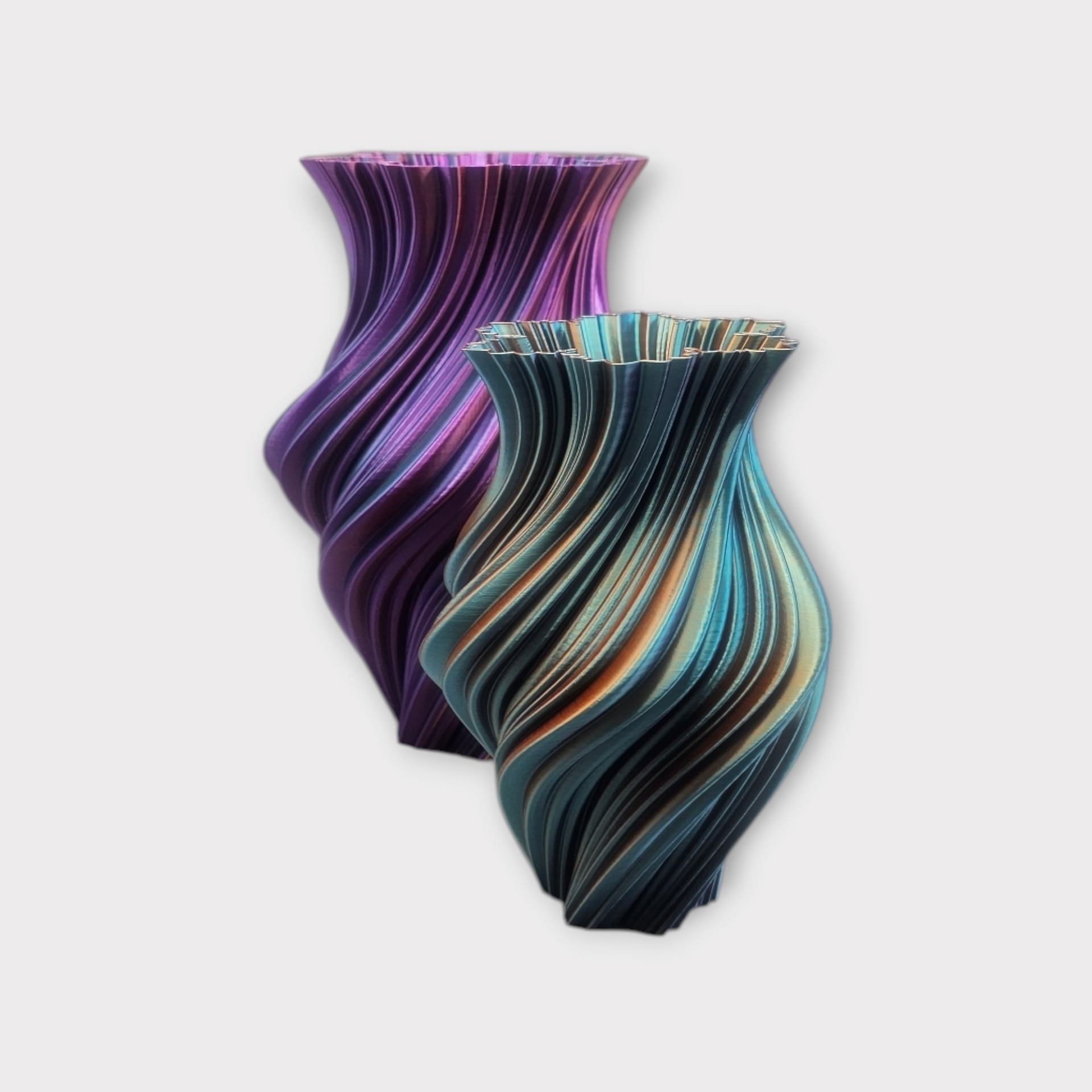 Twee 3D-geprinte vazen met een spiraalvormig, geribbeld ontwerp; de ene is metallic paars, de andere heeft een blauw-gouden kleurovergang.