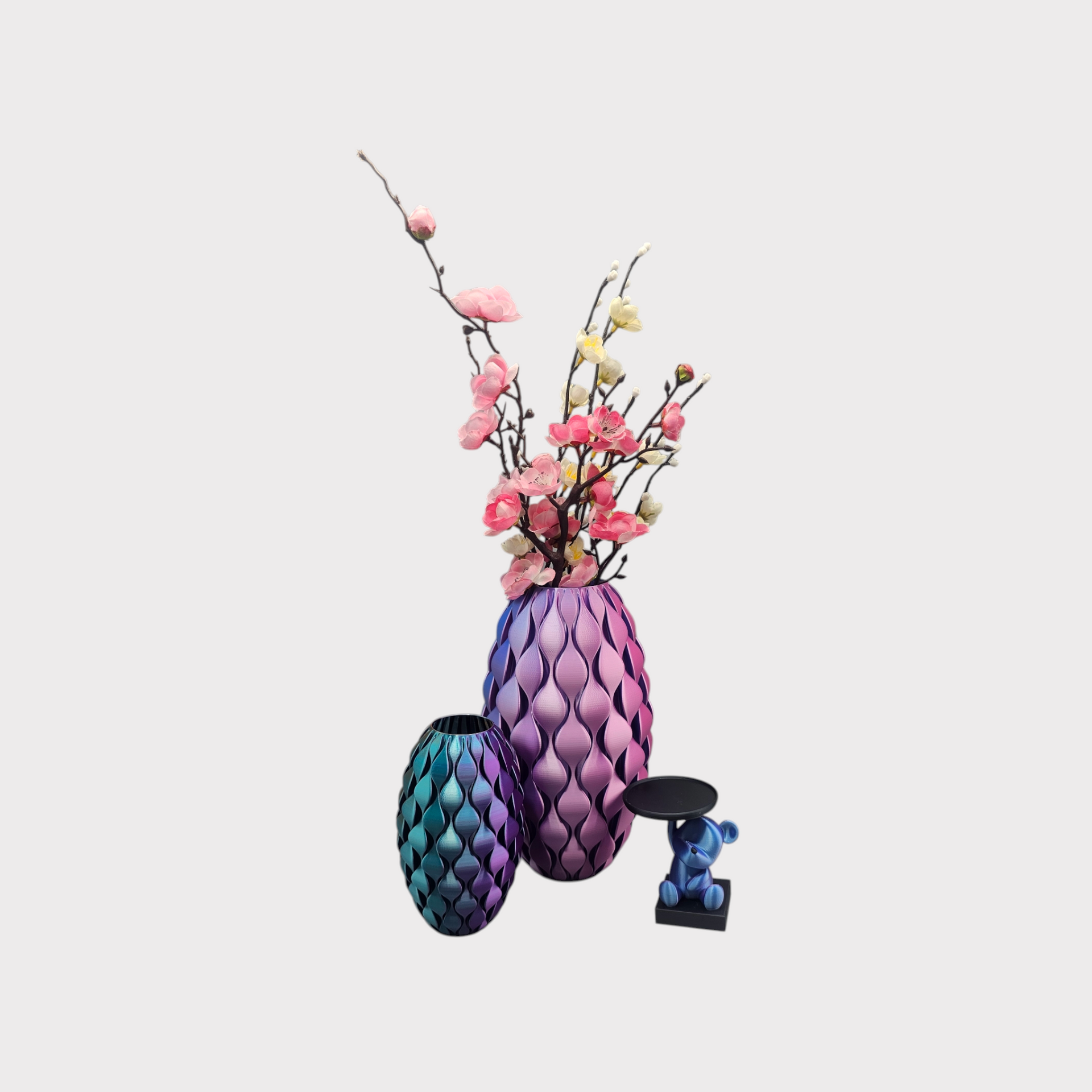 Een ovaalvormige, 3D-geprinte vaas met een verticaal, herhalend golfpatroon, waarvan de kleur overgaat van paars naar perzik.