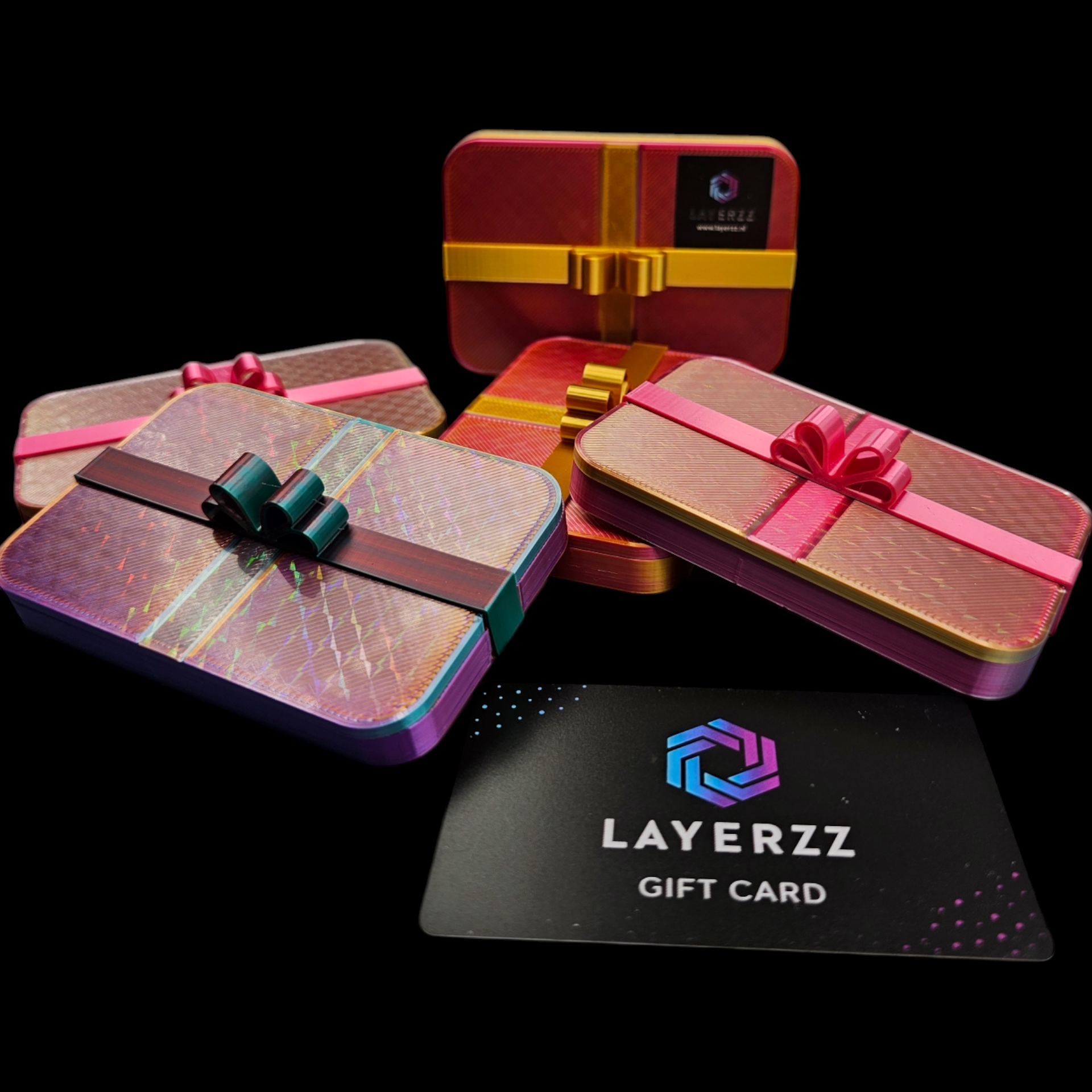 Cadeauverpakkingen in rode, roze en holografische kleuren met een Layerzz-cadeaukaart op een zwarte achtergrond.