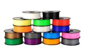 Kleurrijke spoelen 3D-printfilament opgestapeld in een piramidevorm; bevat verschillende kleuren zoals zwart, wit, rood en blauw.