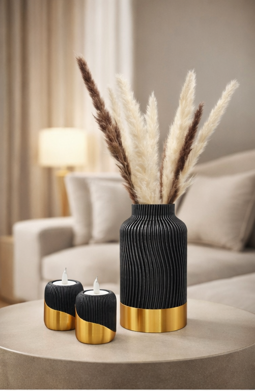Een zwarte vaas met textuur en gouden rand, gevuld met pampasgras, staat samen met twee bijpassende kandelaars op een ronde tafel.