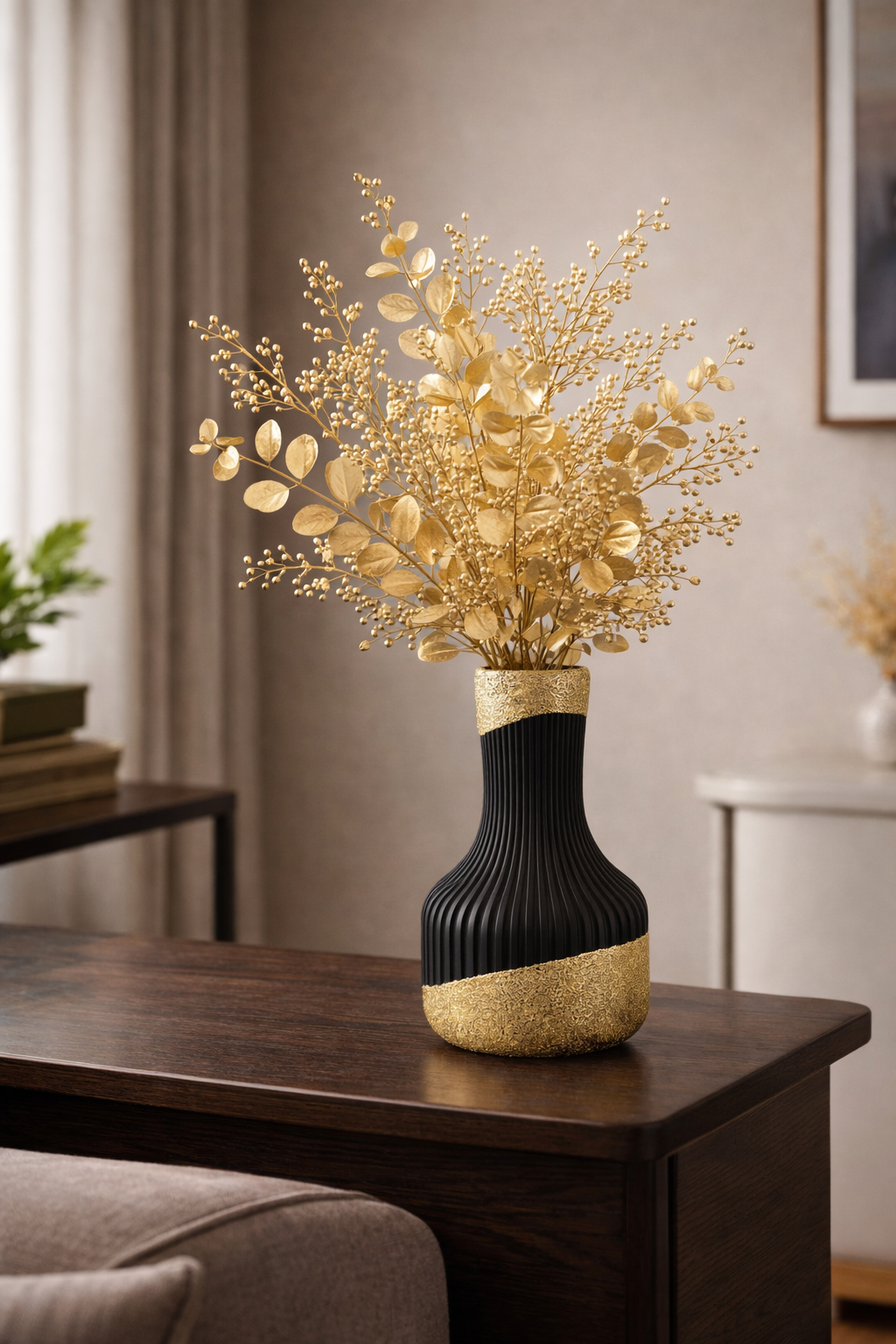 Een decoratieve zwart-gouden vaas gevuld met goudkleurige, bladerrijke takken staat op een donkere houten tafel in een kamer.