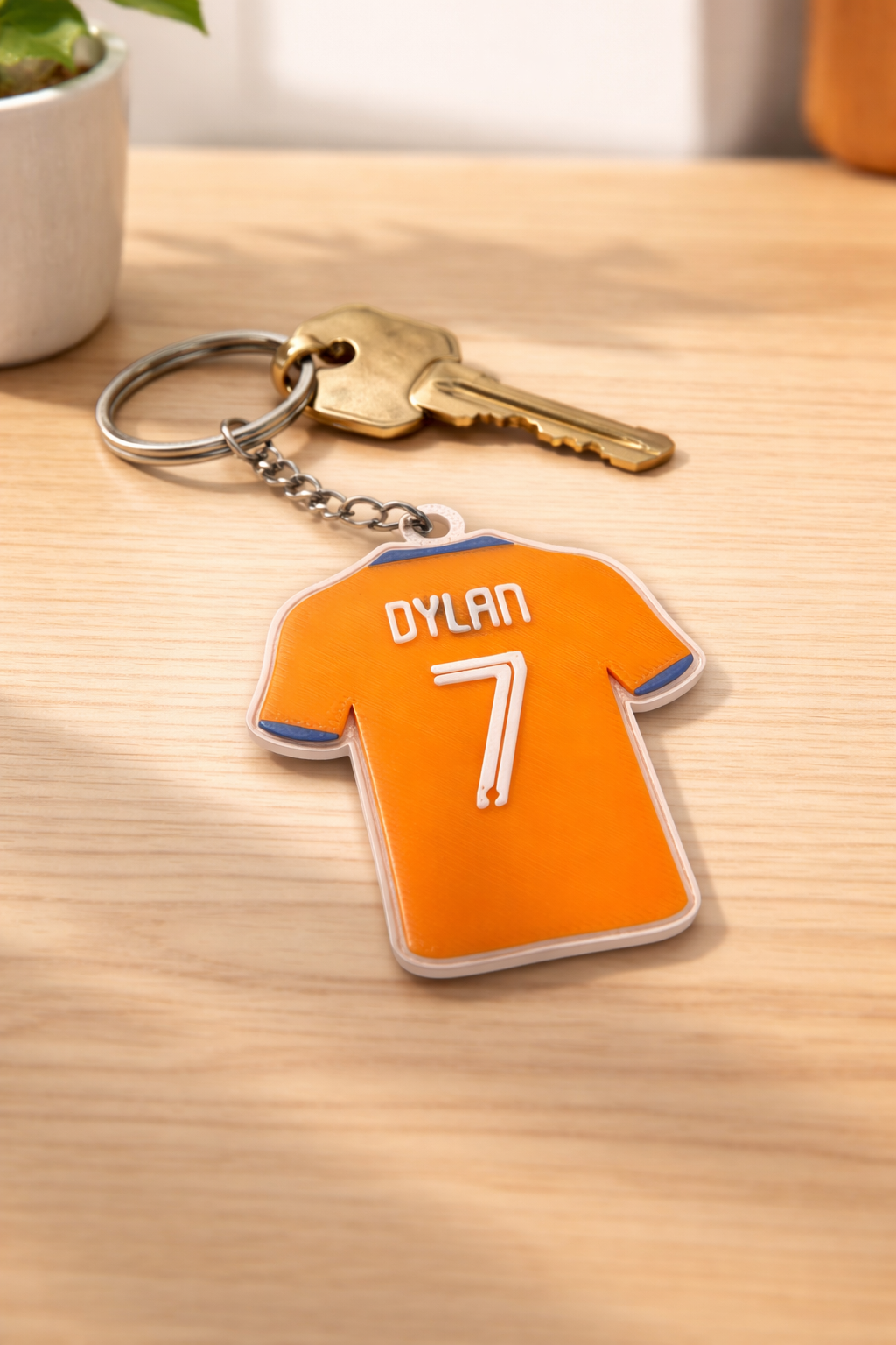 Een oranje, shirtvormige sleutelhanger met de naam