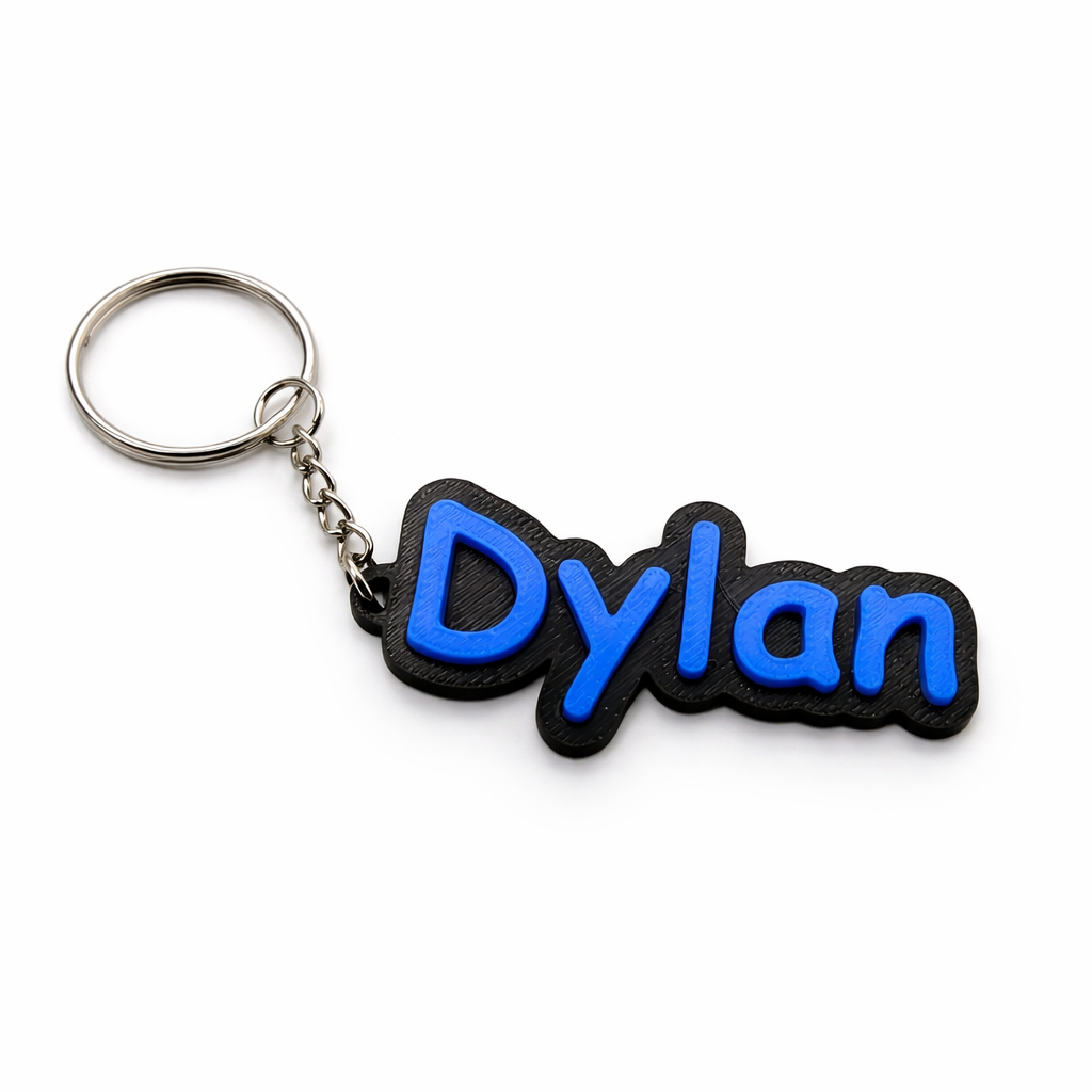 Een zwarte, 3D-geprinte sleutel hanger met de naam "Dylan" in reliëf, felblauwe letters, bevestigd aan een metalen ring.