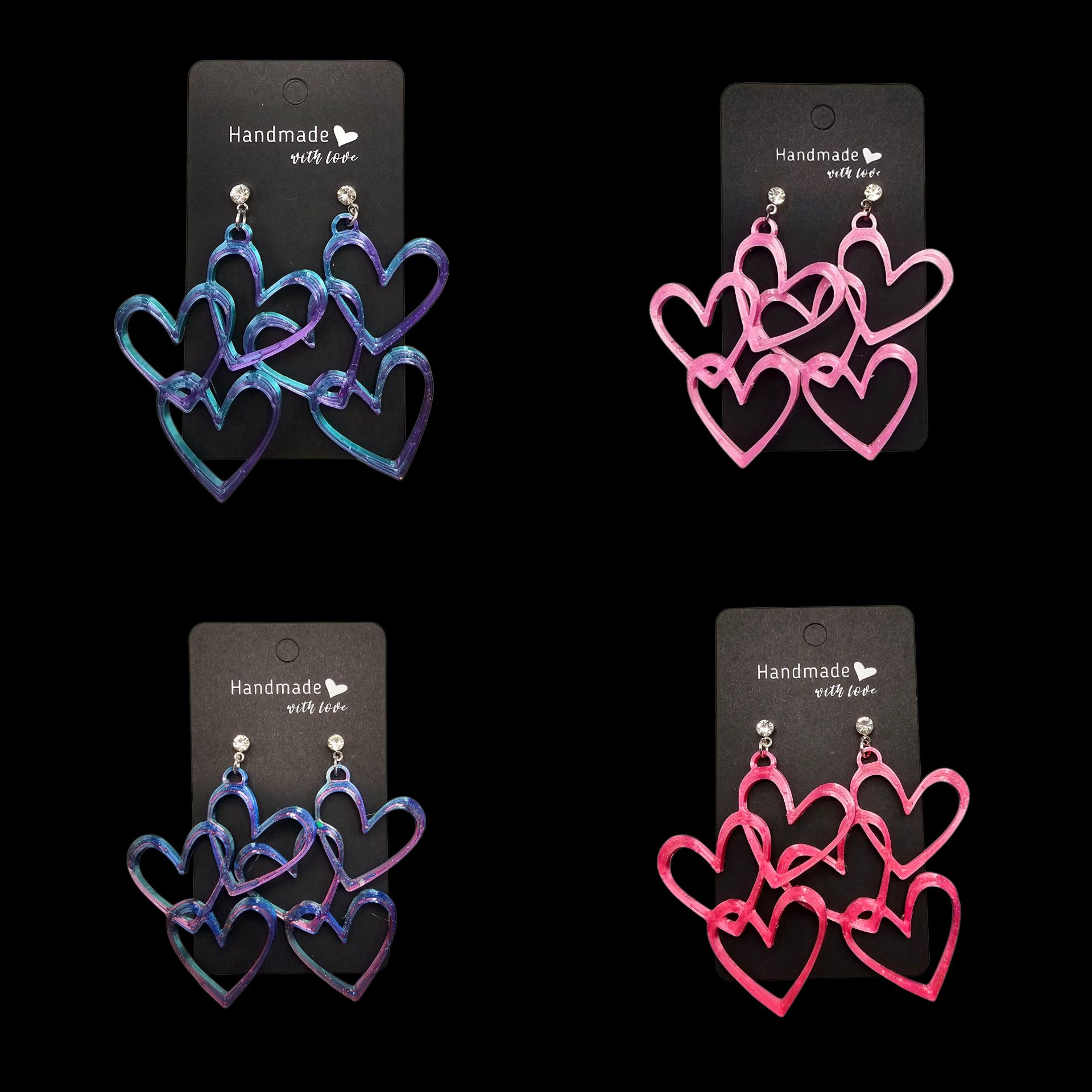 Vier paar hangende hartvormige oorbellen in blauwpaarse en roze kleurschakeringen, gepresenteerd op handgemaakte zwarte kaartjes.