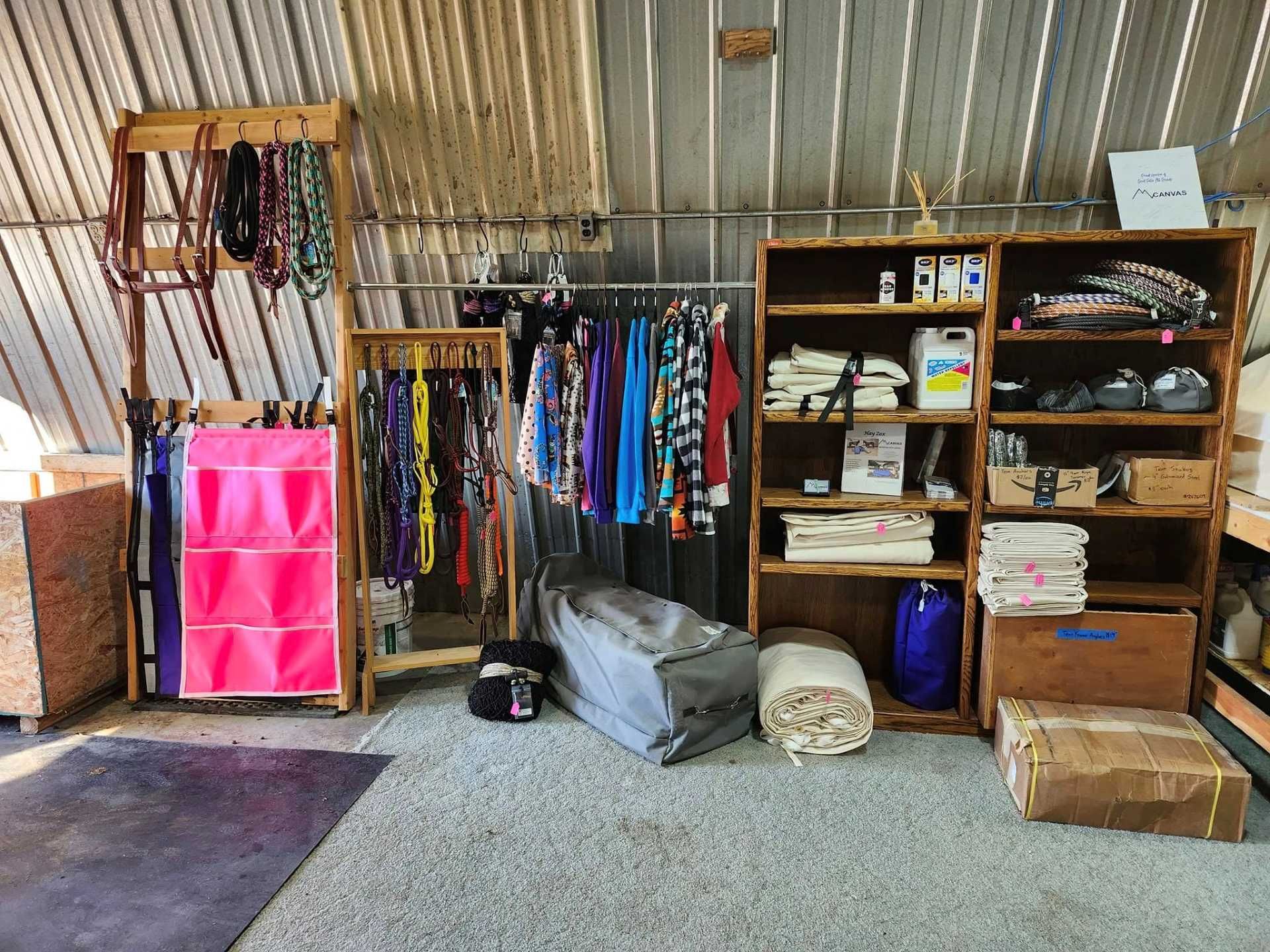 A tack room with wooden shelves displaying various horse equipment, apparel, colorful bridles, and organized storage.