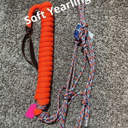 An orange and patterned rope halter with a matching orange braided lead, laid flat on a gray carpet.