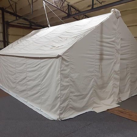 A large, beige, rectangular canvas tent with a gabled roof set up indoors on a gray floor.