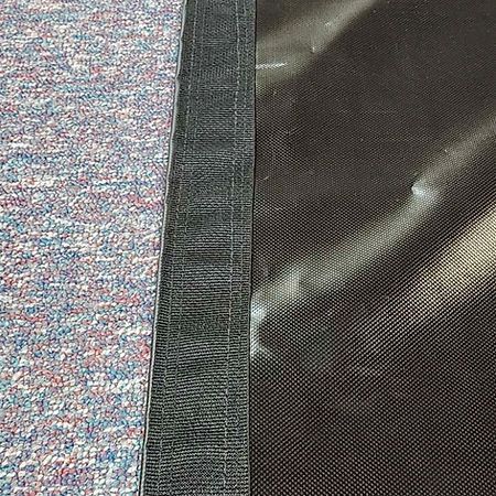 Close-up of a dark grey textured fabric edge joined to a multicolored speckled fabric.