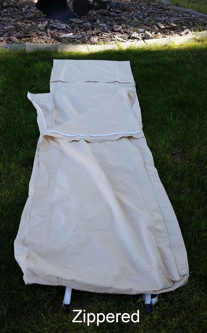 A cream-colored sleeping bag lies on a green grass lawn, partially unzipped.