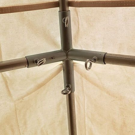 A close-up view of the metal T-shaped corner connector joining three tent poles with silver eyelet screws inside a tent.