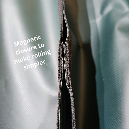 A close-up of a silver-grey fabric roll with a brown textured trim featuring a magnetic closure for easier rolling.