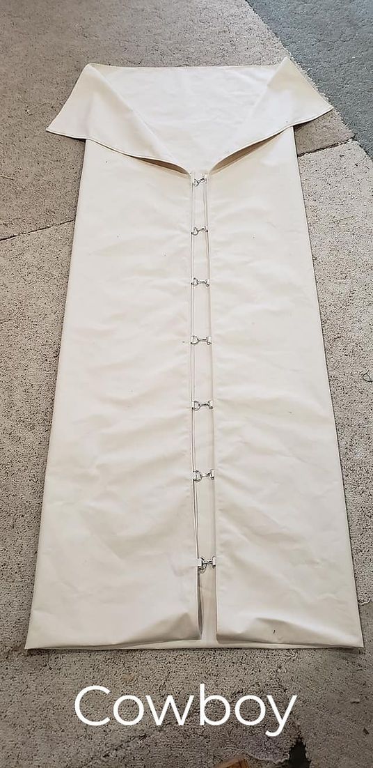 A cream-colored canvas bedroll with a triangular flap and metal closure rings, labeled "Cowboy" at the bottom.