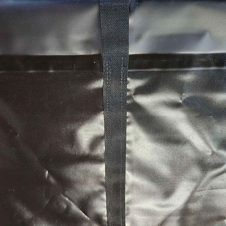 A close-up of a black, textured fabric surface with a vertical, stitched fabric strip running down the center.